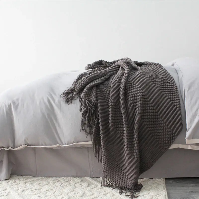 Dark Gray textured blanket draped over a bed with light gray bedding.