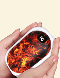 Close-up of hands holding the EmberGlow hand warmer with ember heating effect and a 60°C display.
