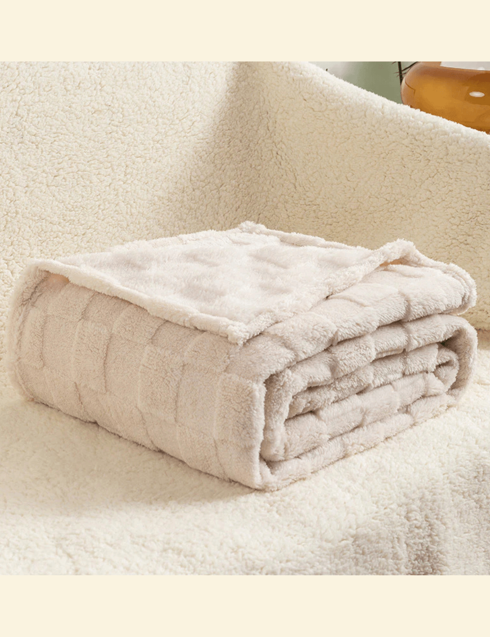 Beige Warmweave checkered blanket folded neatly on a soft cream sofa