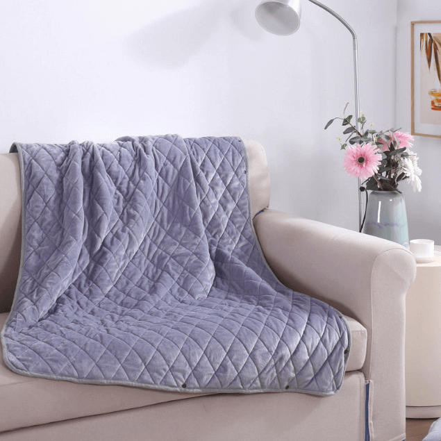 Ash Stone heated blanket shown on a modern chair with gentle folds