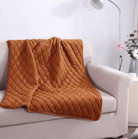 Toffee Ember heated blanket draped over a white sofa with quilted pattern