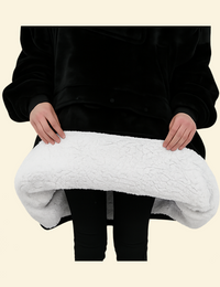 Hands lifting the edge of the black heated hoodie blanket to reveal white sherpa interior