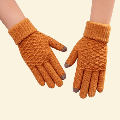 A pair of WarmWeave knit gloves in Amber Glow orange, featuring a cozy diamond-knit pattern and brown touchscreen fingertips, displayed on a soft cream background.

