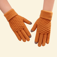 A pair of WarmWeave knit gloves in Amber Glow orange, featuring a cozy diamond-knit pattern and brown touchscreen fingertips, displayed on a soft cream background.

