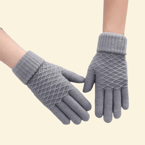 A pair of WarmWeave knit gloves in Ash Grey with a textured diamond-knit pattern and ribbed cuffs, displayed against a neutral cream background.

