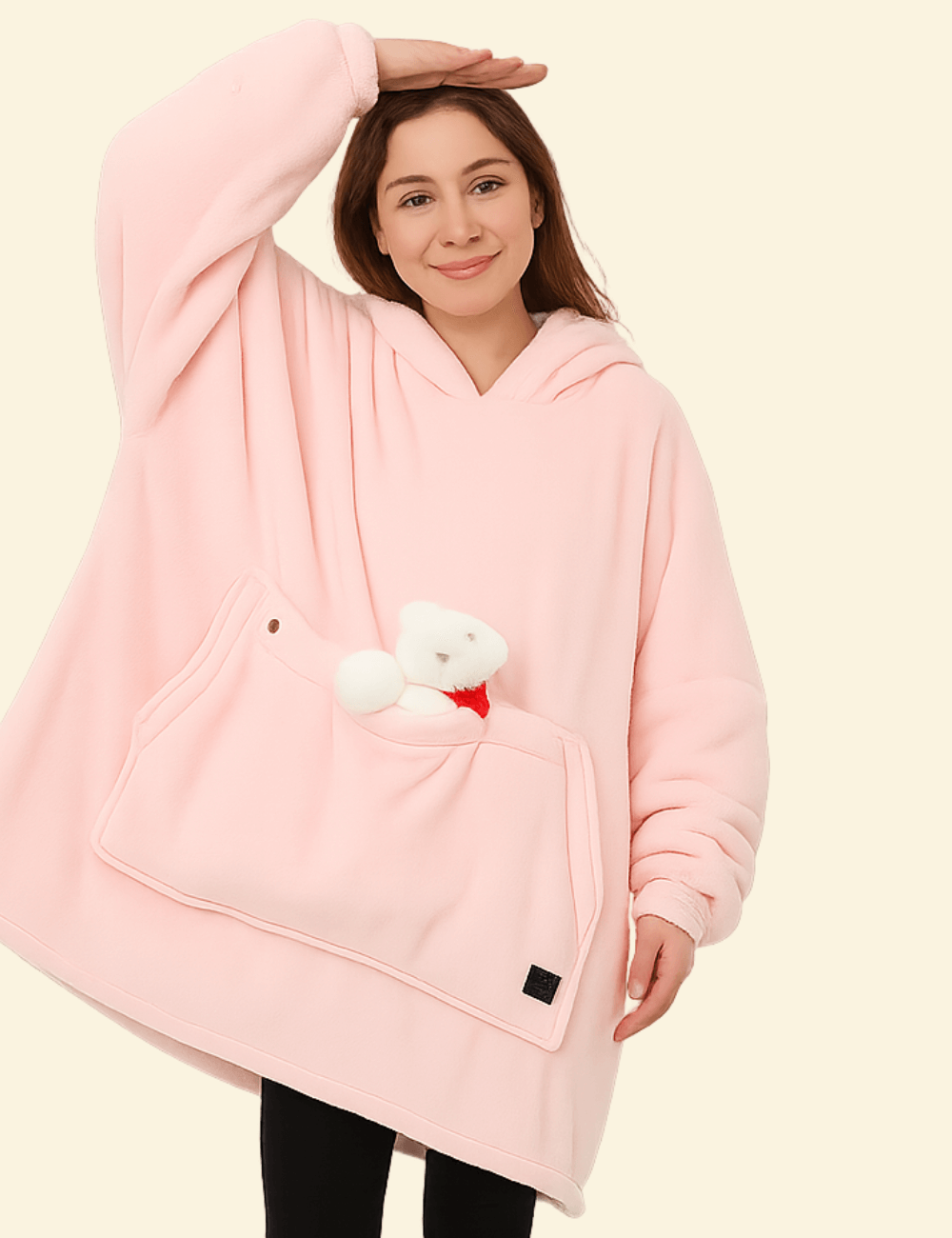 Woman in a soft pink wearable blanket holding a small plush bear in the front pocket