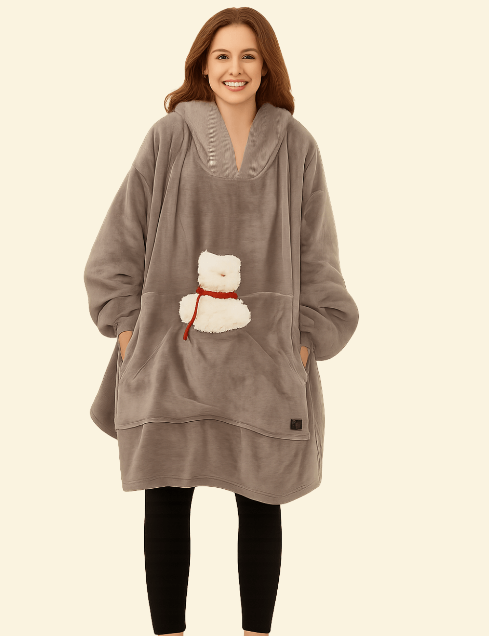 Woman in taupe grey oversized heated hoodie blanket holding plush bear