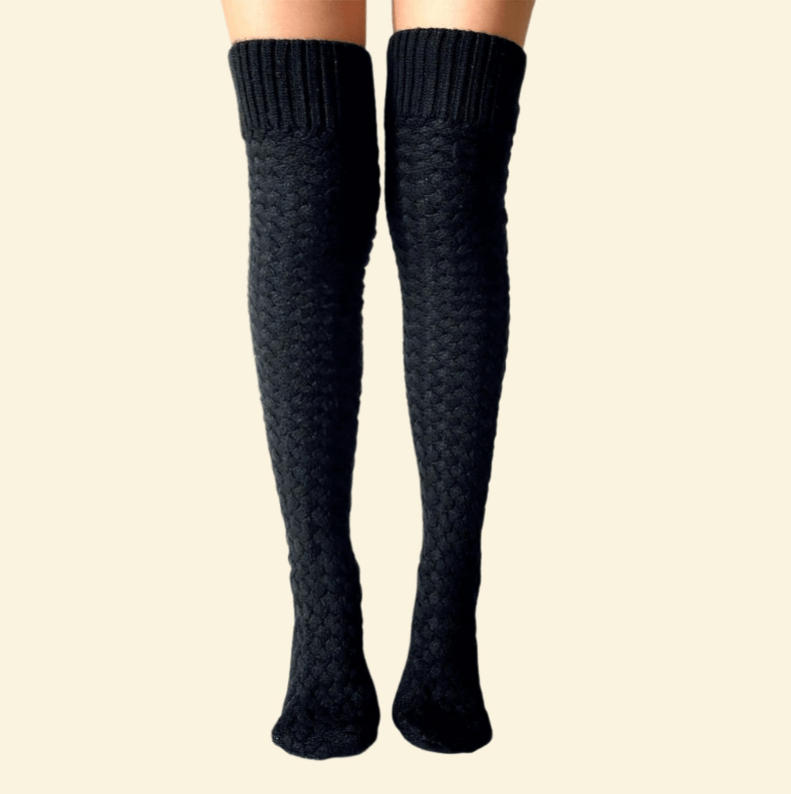 Long black thermal knee-high socks worn on legs against a cream background