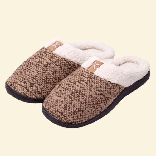 Sandstone memory foam slippers with cream sherpa lining and black sole on beige background
